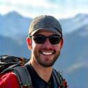 Un escursionista sorride davanti a un panorama montano.